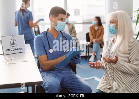 Medico che parla con paziente anziano della signora prima dell'appuntamento in ospedale Foto Stock