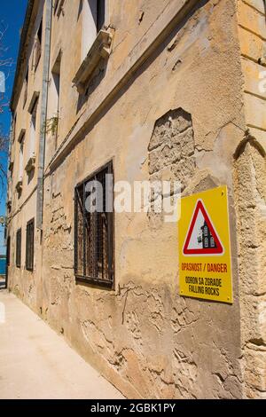 Un segno su una casa derelict avvertono la gente che la casa è un pericolo, nella storica città costiera medievale di Porec in Istria, Croazia Foto Stock