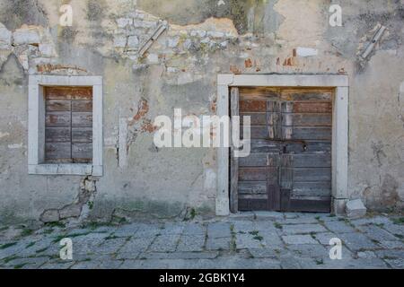 Una porta e una finestra in un vecchio edificio in pietra derelict nella storica città costiera medievale di Porec in Istria, Croazia Foto Stock