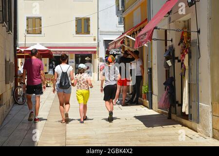 Porec, Croazia - 10 luglio 2021. Una passeggiata in famiglia lungo una strada piena di negozi e turisti nella storica città costiera medievale di Porec in Istria, Cro Foto Stock