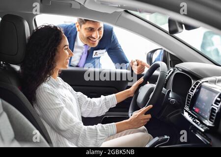 Giovane donna d'affari che acquista una nuova auto di lusso nello showroom Foto Stock