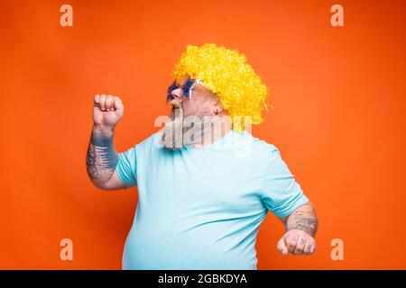 Uomo grasso con barba, tatuaggi e occhiali da sole canta una canzone Foto Stock