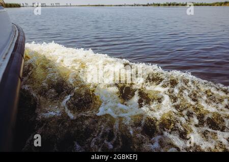 Dettagli con il surf creato da una piccola barca in movimento su un lago. Foto Stock