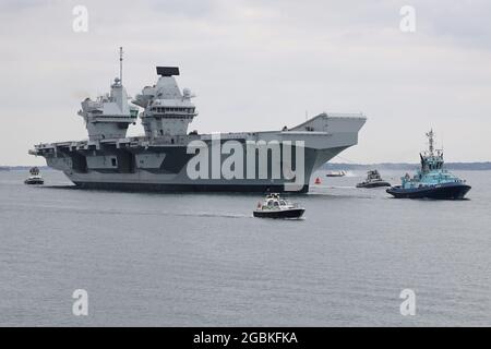 I Tugs guidano la portaerei della Royal Navy HMS PRINCE OF WALES verso la base navale Foto Stock