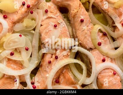Pezzi di trota al forno con cipolle, patate e peperoni rosa, sfondo Foto Stock