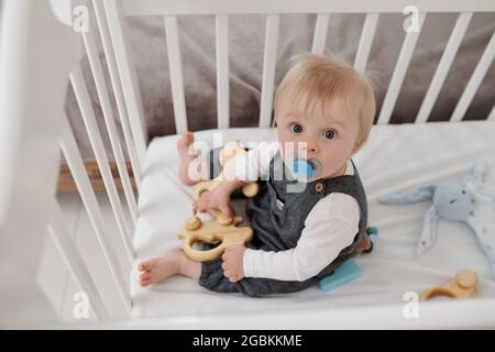 Ritratto di bambino serio con manichino seduto a letto e giocando con giocattolo di legno Foto Stock