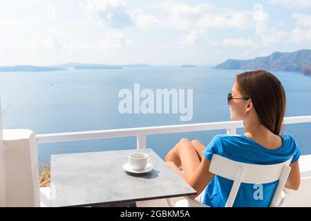 Donna che si rilassa sul balcone dell'hotel godendo della vista mare bevendo una tazza di caffè durante la prima colazione del mattino. Resort di lusso viaggio vacanza stile di vita ragazza seduta a. Foto Stock