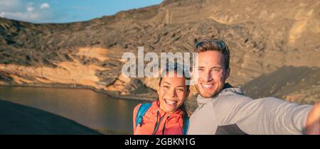 Viaggi coppie interrazziali turisti in viaggio in Spagna scattando foto selfie in escursione. Banner panoramico di donna asiatica, uomo caucasico escursionisti felici Foto Stock