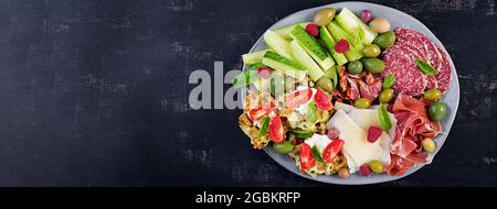 Lavagna di salumi. Piatto: parmigiano con prosciutto, salame, cetrioli e olive. Assortimento di gustosi antipasti o antipasti. Vista dall'alto, spazio di copia, Foto Stock