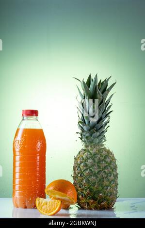 Succo di agrumi e ananas. Ananas e arance volanti. Centrifugare in una bottiglia di plastica. Foto Stock