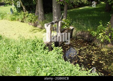 Bezzetto di calcestruzzo in un fossato con una slitta azionata manualmente. Nel Nord Olanda, Paesi Bassi. Estate, agosto. Foto Stock