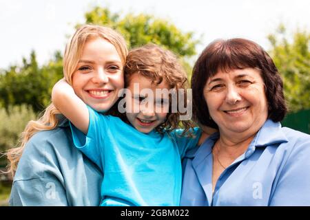 Ragazza carina che abbraccia madre e nonna all'aperto Foto Stock