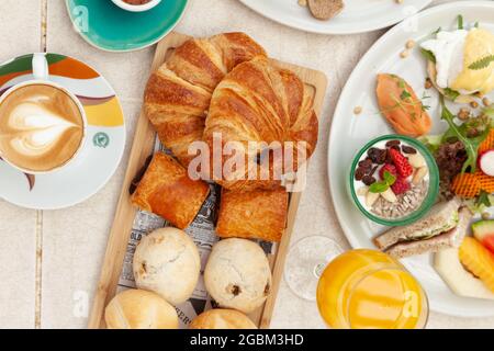 Vista dall'alto su croissant, dolci diversi con una tazza di latte e succo d'arancia con altri spuntini Foto Stock