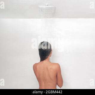 Stile di vita della doccia. Donna che prende una vasca calda doccia lavando i suoi capelli nel lussuoso bagno dell'hotel con doccia a pioggia. Vista da dietro Foto Stock