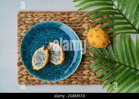 Il dragonfruit di pitaya giallo affettato presentato su piatto blu sul tavolo. Frutta di drago biologica fresca e sana. Ilocereus megalanthus Foto Stock