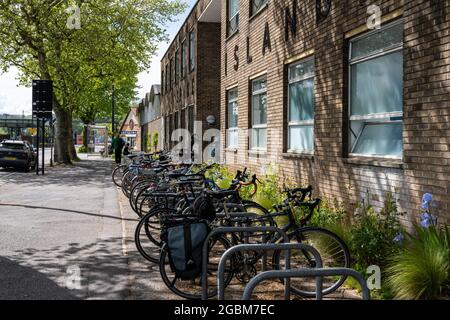 Una fila di portabiciclette "Sheffield stand" posizionate in modo preminente e comodo all'esterno dell'ingresso principale di un edificio, con spazio per cicli non standard Foto Stock