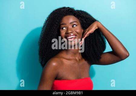 Foto di affascinante giovane pelle scura donna sguardo vuoto spazio tenere mano faccia isolata su sfondo colore teal Foto Stock