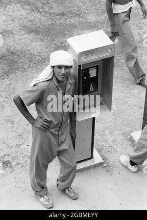 Port Isabel, Texas USA, circa1989: Gli immigrati non documentati presso la struttura di detenzione del Texas meridionale si riuniscono intorno ai telefoni a pagamento per chiamare i membri della famiglia o il consulente legale. ©Bob Daemmrich Foto Stock