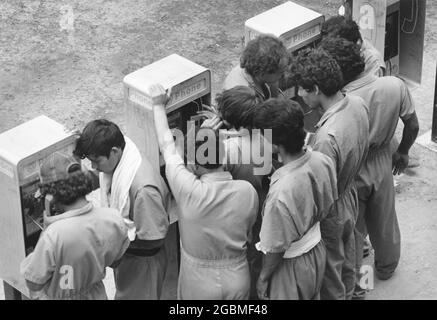 Port Isabel, Texas USA, circa1989: Gli immigrati non documentati presso la struttura di detenzione del Texas meridionale si riuniscono intorno ai telefoni a pagamento per chiamare i membri della famiglia o il consulente legale. ©Bob Daemmrich Foto Stock