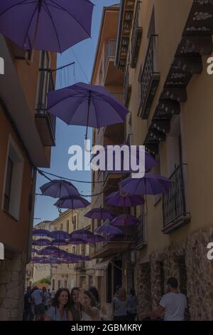 BRIHUEGA, SPAGNA - 10 luglio 2021: Un tiro a basso angolo di ombrelli viola che decorano le strade di Brihuega nel mese di luglio Foto Stock