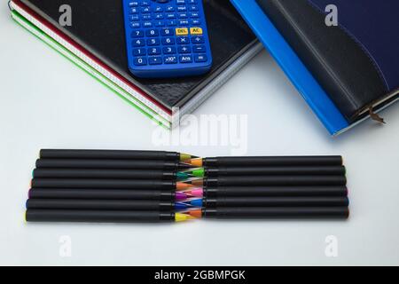 gruppo di strumenti scolastici con notebook, pennarelli, penne, clip, calcolatrice e regole pronte per il ritorno a scuola su sfondo bianco Foto Stock