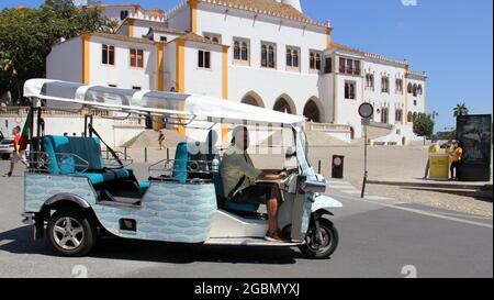 Auto risciò 'tuk-tuk' a Sintra, il Palazzo di Sintra sullo sfondo, Portogallo Foto Stock