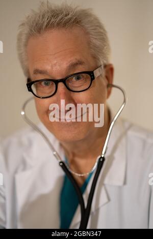 Bel medico maschio maturo sorridente con stetoscopio nelle orecchie Foto Stock
