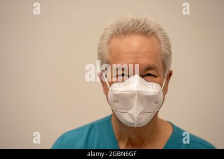 Bell'infermiera di vecchio uomo sorridente con una maschera facciale Foto Stock