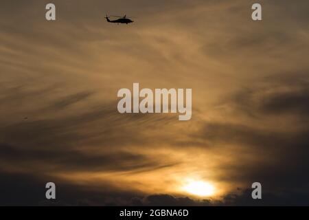 Una silhouette di un elicottero US Navy Sikorsky SH-60R Seahawk con il Maritime Strike Squadron 51 contro un cielo nuvoloso e al tramonto vicino a NAF Atsugi, Giappone Foto Stock