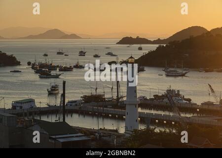 Tramonto sulla città e il porto di Labuan Bajo, con molte navi da crociera tradizionali Phinisi ancorate come la città è il punto di ingresso al Komodo nazionale Foto Stock