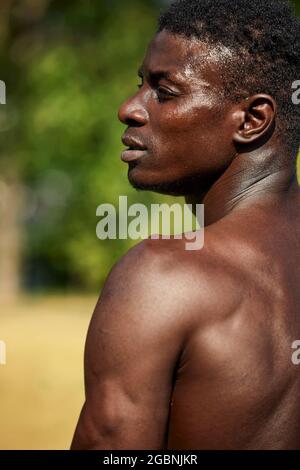 Atleta che riposa tra l'esercizio all'aperto, l'esercizio all'aperto, gli afroamericani che si esercitano sul terreno sportivo, l'ambiente urbano, primo piano, back shot. Foto Stock