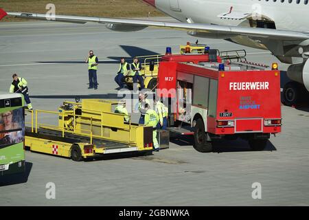 INNSBRUCK, AUSTRIA - 27 febbraio 2020: Un operaio maschile nel reparto vigili del fuoco dell'aeroporto e altri veicoli a Innsbruck, Austria Foto Stock