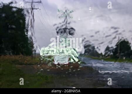 Una giornata di pioggia cupa e guardando attraverso la finestra frizzly verso un attraversamento ferroviario di paese Foto Stock