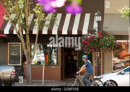Un uomo guida la sua bicicletta passando per la zona ovest di Seattle, Bakery Nouveau, Seattle, Washington. Foto Stock