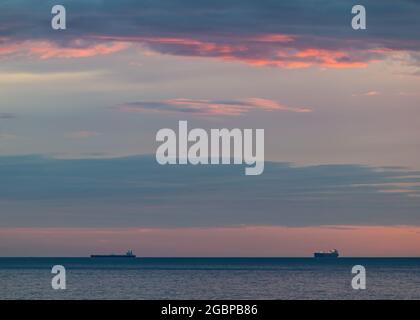 Scozia, Regno Unito, 5 agosto 2021. Alba: Il sole sorge sull'orizzonte con la sagoma delle navi da trasporto all'orizzonte nel Mare del Nord Foto Stock