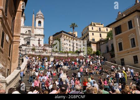 Vista sulla famosa, ampia e affollata scalinata scalinata di Piazza di Spagna, con sullo sfondo la chiesa Trinità dei Monti e l'obelisco. A Roma, Italia. Foto Stock