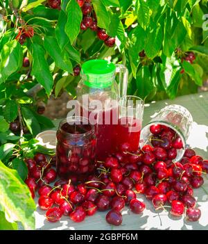 Ciliegie dolci fresche, barattolo di composto e succo in caraffa in frutteto Foto Stock