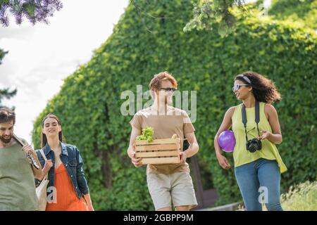 Ragazze e ragazzi che comunicano andando al picnic Foto Stock