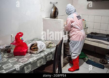 Bogor, Indonesia. 04 agosto 2021. Nurhasanah preparazione di un pasto per il paziente.Nurhasanah (37) un membro del volontario Polisi Masyarakat si prende cura di un paziente disabile sospettato di essere con Covid-19 sotto l'auto isolamento in corso. Lapor Covid-19, una coalizione della società civile che ha crowdsources le informazioni del coronavirus in tutto il paese ha riferito il tasso di morti di Covid-19. (Foto di Wisnu Agung Prasetyo/SOPA Imag/Sipa USA) Credit: Sipa USA/Alamy Live News Foto Stock