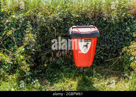 Un contenitore per lo smaltimento dei rifiuti di cani in una corsia di campagna. Foto Stock