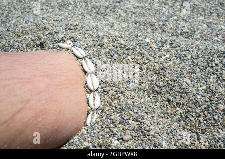 Bracciale a conchiglia su mezza gamba maschile sepolta. Simbolo dell'ora legale Foto Stock