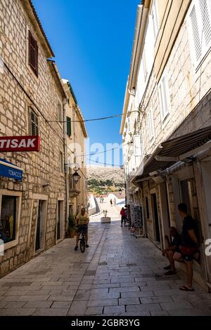 PAG, CROAZIA - 13 luglio 2021: Un colpo verticale di persone che camminano su una strada stretta con negozi nella città di Pag, Croazia Foto Stock