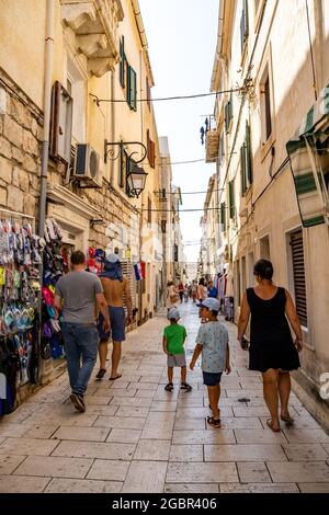 PAG, CROAZIA - 13 luglio 2021: Un colpo verticale di persone che camminano su una strada stretta con negozi nella città di Pag, Croazia Foto Stock