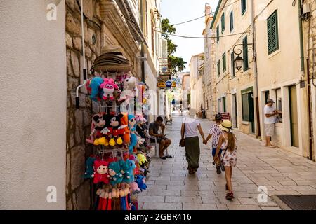 PAG, CROAZIA - Luglio 13, 2021: Un piccolo negozio di articoli da regalo e persone che camminano in una strada stretta nella città di Pag, Croazia Foto Stock