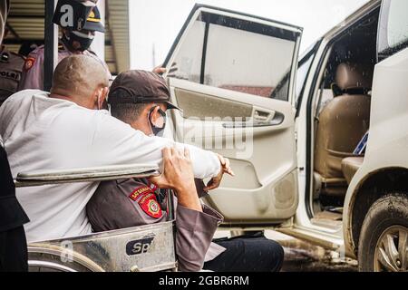 Kendari, Indonesia. 05 agosto 2021. Un poliziotto Kendari aiuta un uomo disabile ad entrare in macchina. La cabina di Kendari per i vaccini della polizia ha organizzato un'operazione di vaccinazione per i disabili presso la stazione di polizia di Mandonga a Kendari. Decine di persone disabili sono state raccolte presso le loro rispettive case utilizzando i veicoli operativi della polizia per la loro prima dose del vaccino Sinovac, Covid-19. (Foto di Andry Denisah/SOPA Images/Sipa USA) Credit: Sipa USA/Alamy Live News Foto Stock