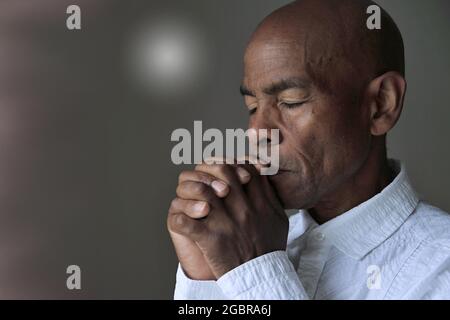 Uomo che prega a dio con le mani insieme Caribbean uomo che prega con sfondo foto stock Foto Stock