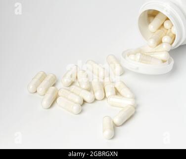 polvere medica in capsule bianche su fondo bianco. Pillole di trattamento, integratori alimentari. Sfondo bianco Foto Stock