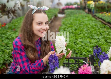 felice infanzia. felice adolescente fiorista in serra. primavera ed estate. Foto Stock