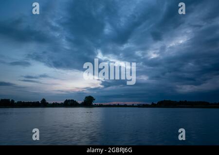 Cielo notturno nuvoloso su un lago calmo Foto Stock