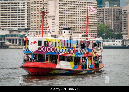 La 'Night Star', una delle flotte Star Ferry, attraversando Victoria Harbour a Kowloon, con il Molo dei Traghetti di Tsim Sha Tsui sullo sfondo Foto Stock